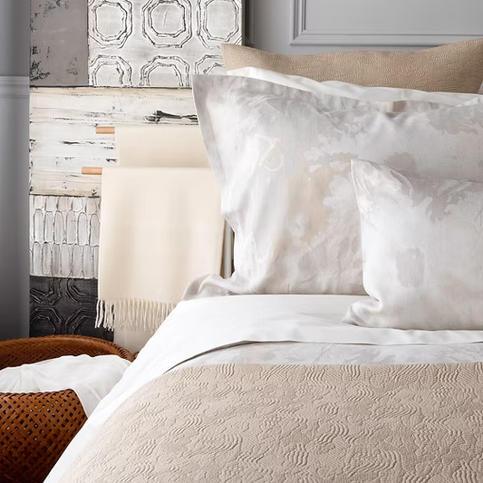 Neatly made bed with Blossom Jacquard Duvet Covers set and pillows against a decorative wall.