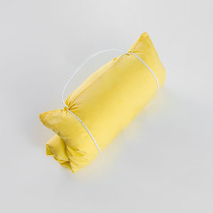 Yellow fabric travel pillow sham rolled on a light gray background