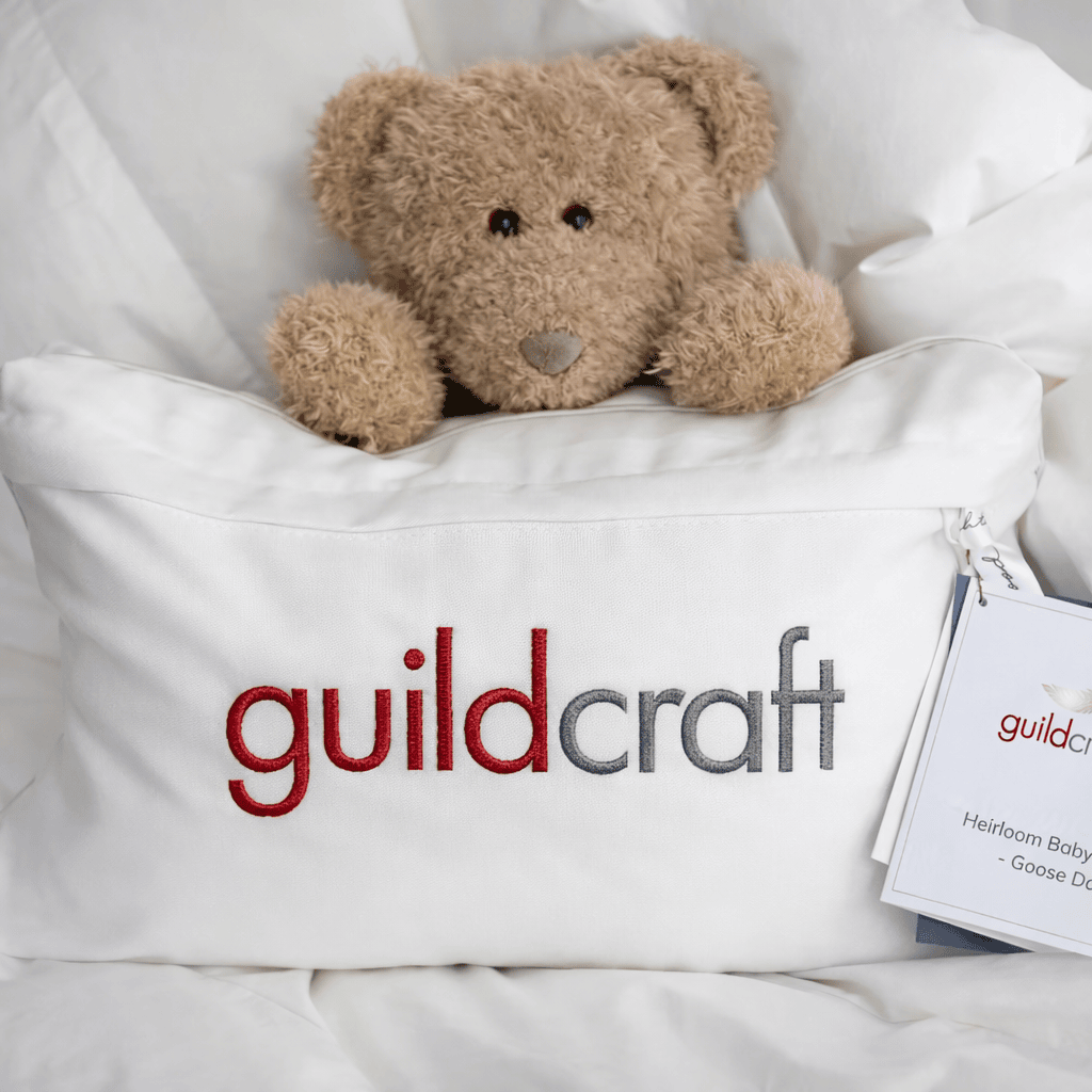 Teddy bear in a Guildcraft Heirloom Baby Duvet with visible branding