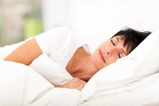 Woman sleeping peacefully under a white down duvet.
