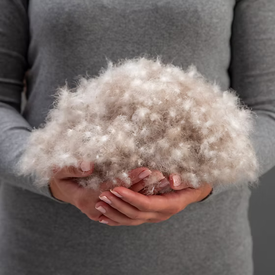 Person holding a large ball of premium down against a gray background
