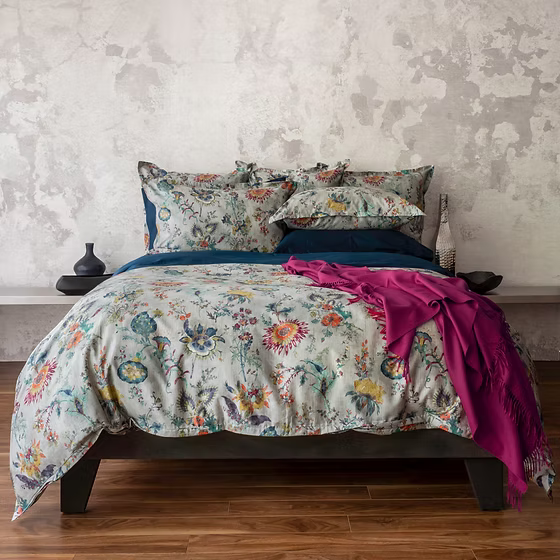 Floral Morgan sateen bedding set with a pink throw on a bed against a textured wall.
