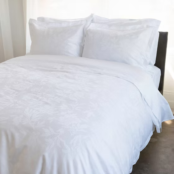 White Giza 92 Flora | Jacquard bedding set on a bed with light-colored curtains in the background