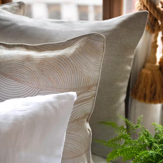 Close-up of decorative pillows in Saturna Jacquard with a plant in the foreground.