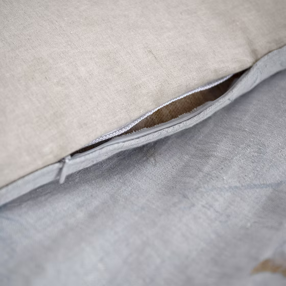 Close-up of a Fortuna Jacquard pillow with a zipper on a beige background