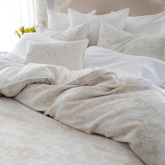 A bed with Sakura jacquard bedding in a gray floral pattern, with a duvet cover and multiple pillows arranged on the bed.