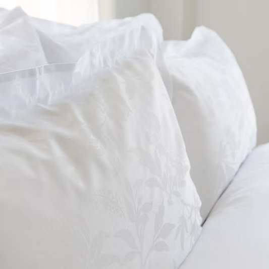 Close-up of a white textured Giza 92 Flora | Jacquard duvet cover on a light background