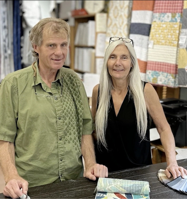 Cindy Guild standing behind a counter with fabric samples in a Guildcraft store.