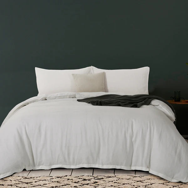 Neatly made bed with French Linen Duvet Cover Set and pillows against a dark wall.