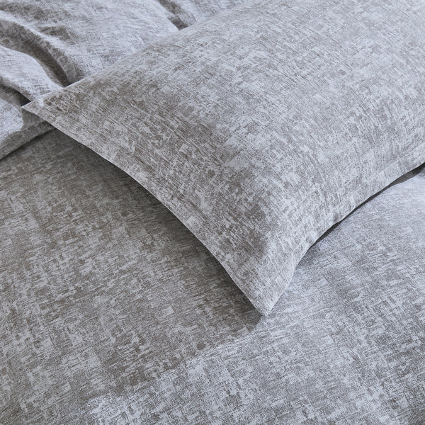 Gray textured Malaga Duvet Cover Set with a pillow on a bed.