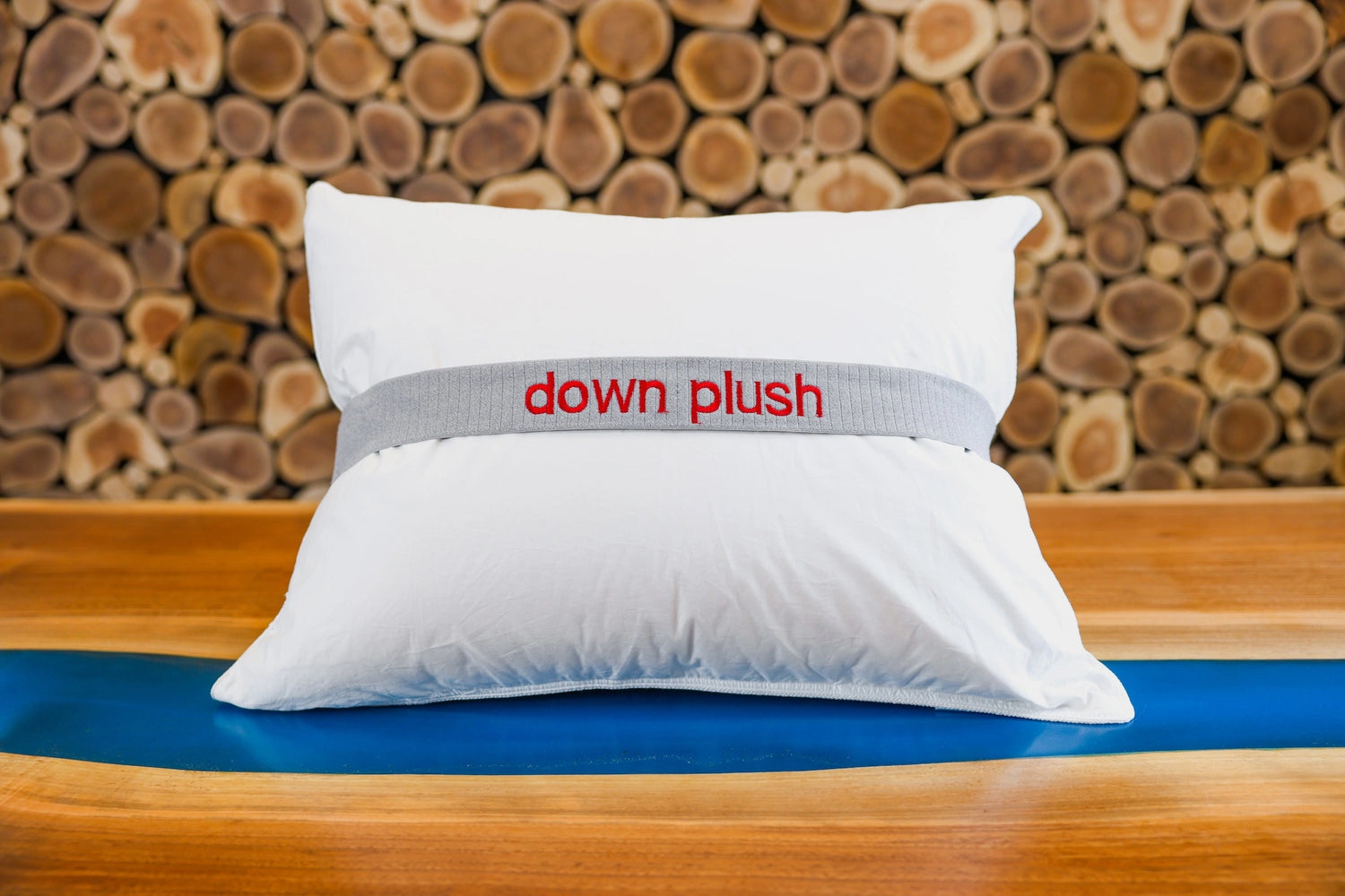 A down plush pillow on a table in front of a wooden wall.