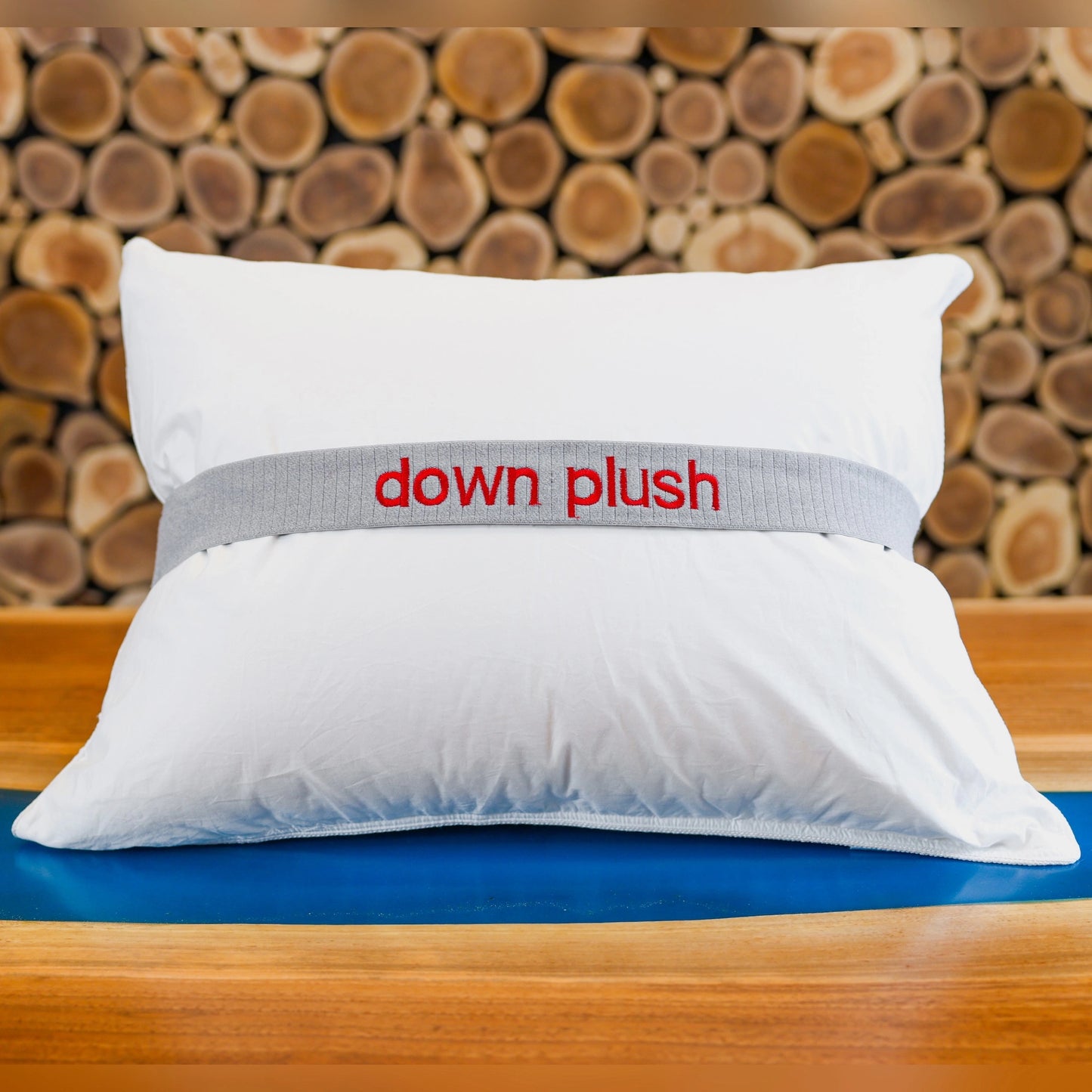Down plus pillow on a table in front of a wooden wall.