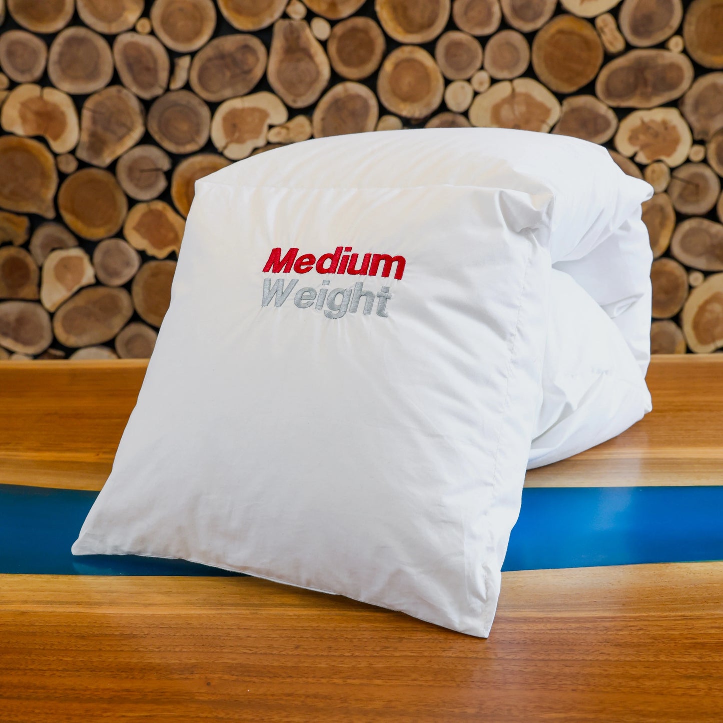 Medium weight Guildcraft's duvet neatly folded on the table in front of a wooden wall.