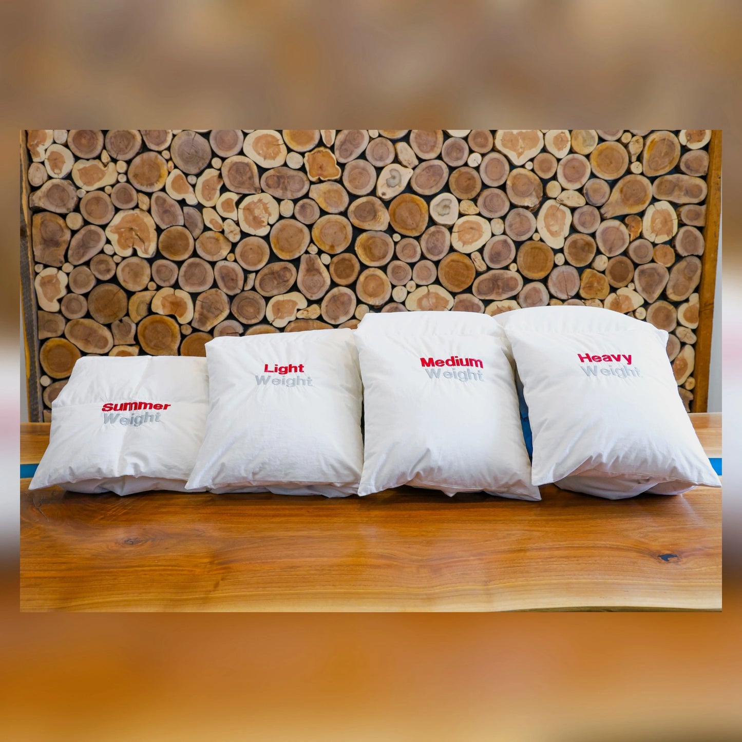 Lineup of duvets in different weights in front of a wooden wall.