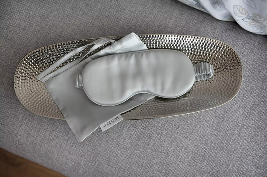 Silk eye mask on a textured tray with a gray background