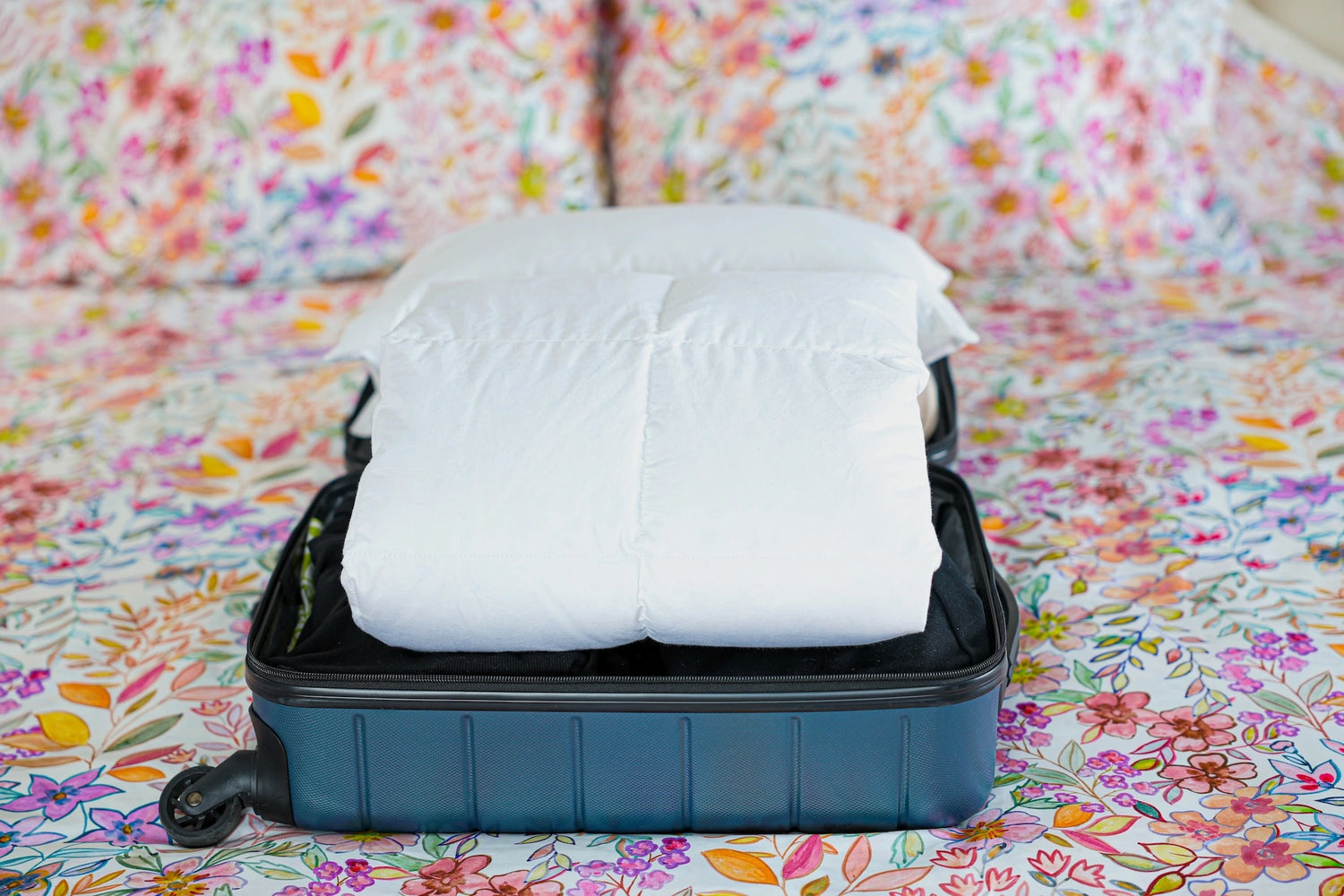 Travel set of travel pillow and a travel duvet packed in a open suitcase.