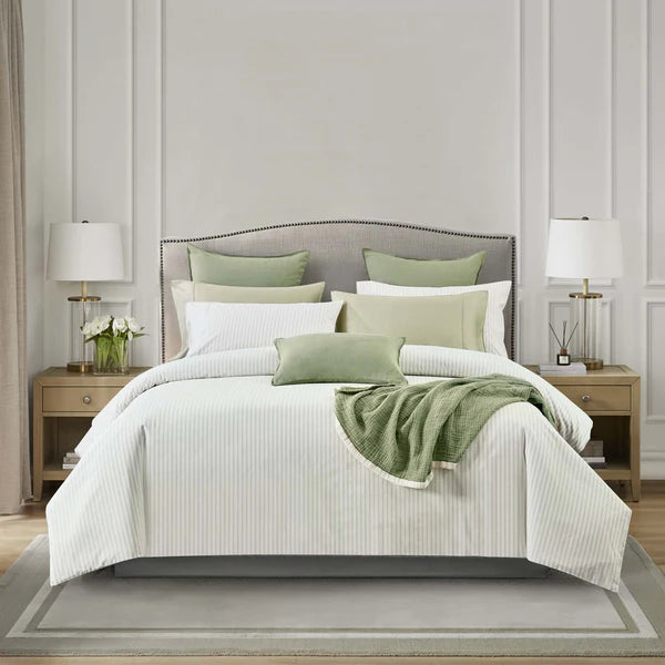 Neatly made bed with white Vale Green Duvet Cover Set and green pillows and blanket in a bedroom setting.
