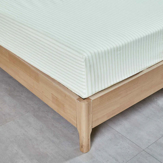 Wooden bed frame with a white mattress on a gray tiled floor and Vale Green Sheet Set