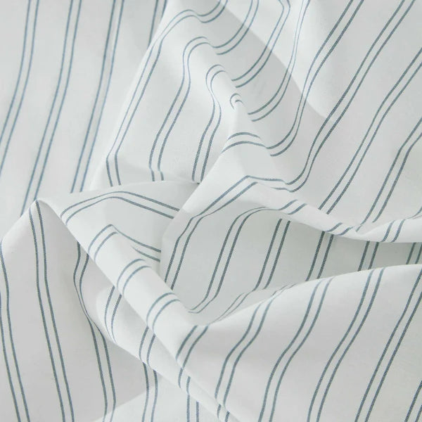 A closeup on a striped fabric of Vale Shadow Sheet Set with blue lines on a white background