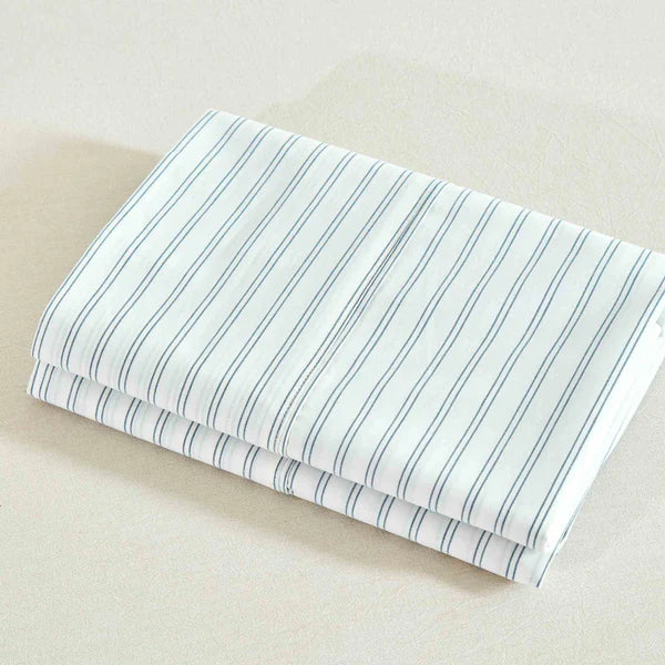 Folded fabric of a Vale Shadow Sheet Set with blue stripes on a beige background