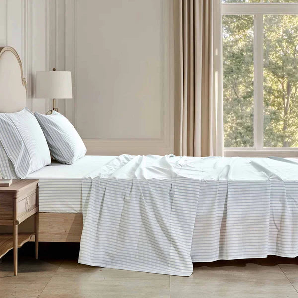 Neatly made bed with striped Vale Shadow Sheet Set in a well-lit bedroom.